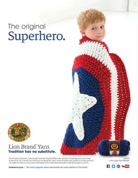 A young boy wrapped in a crocheted blanket styled like a superhero cape, primarily in red, white, and blue with a large white star in the center. He is looking back over his shoulder with a confident smile, conveying a playful superhero pose. The setting is a bright, clean background which enhances the vivid colors of the cape. The text "The original Superhero." 